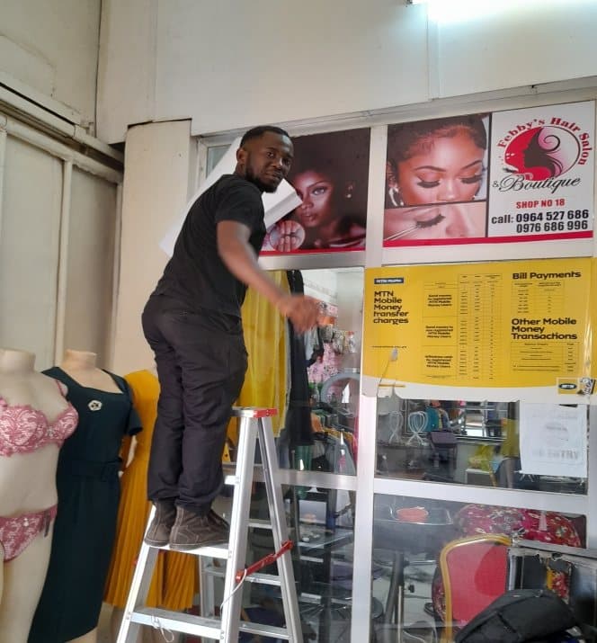 Window graphics and price list being applied to a boutique shopfront