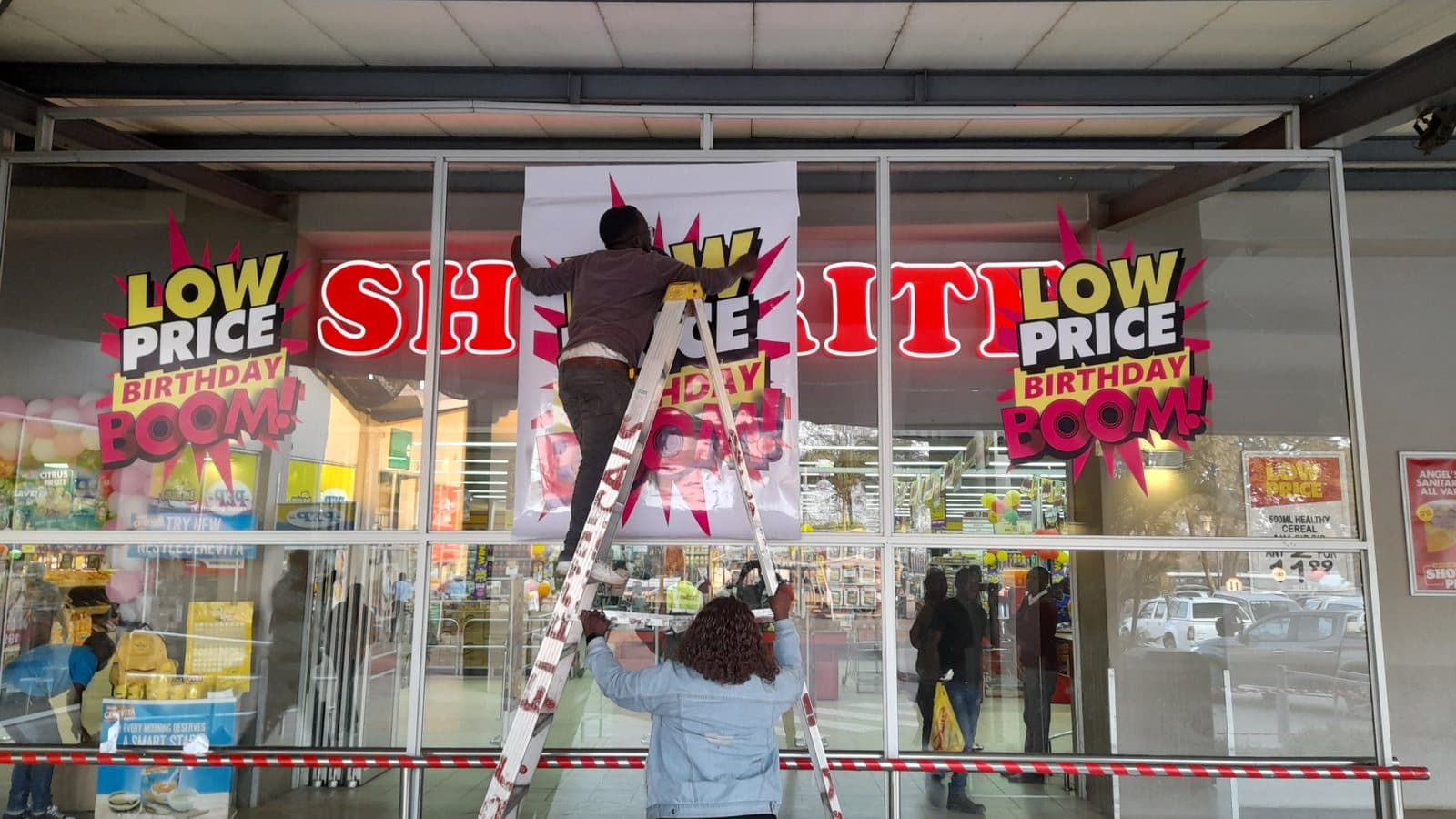 Promotional window graphics installed across a Shoprite storefront
