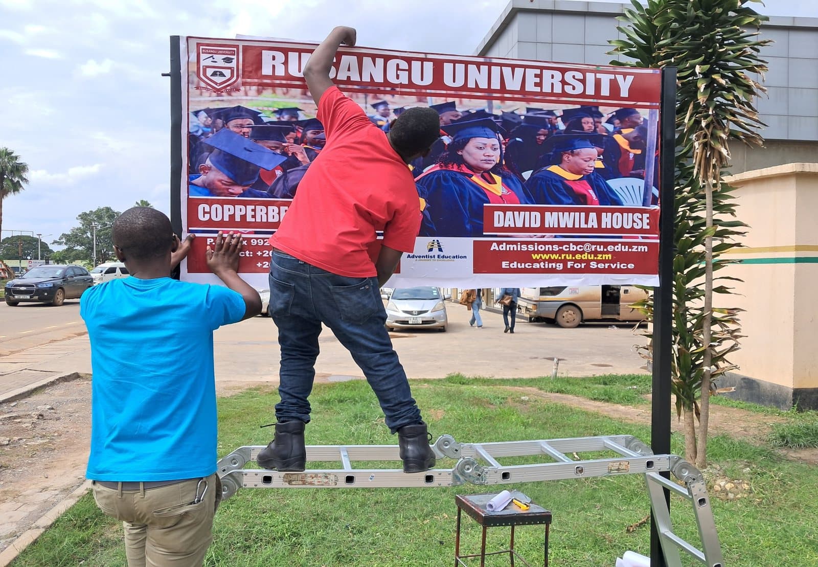 Crew installing a Rusangu University billboard in Kitwe